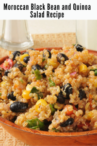 rustic wooden bowl of quinoa black bean and corn salad garnished with fresh herbs