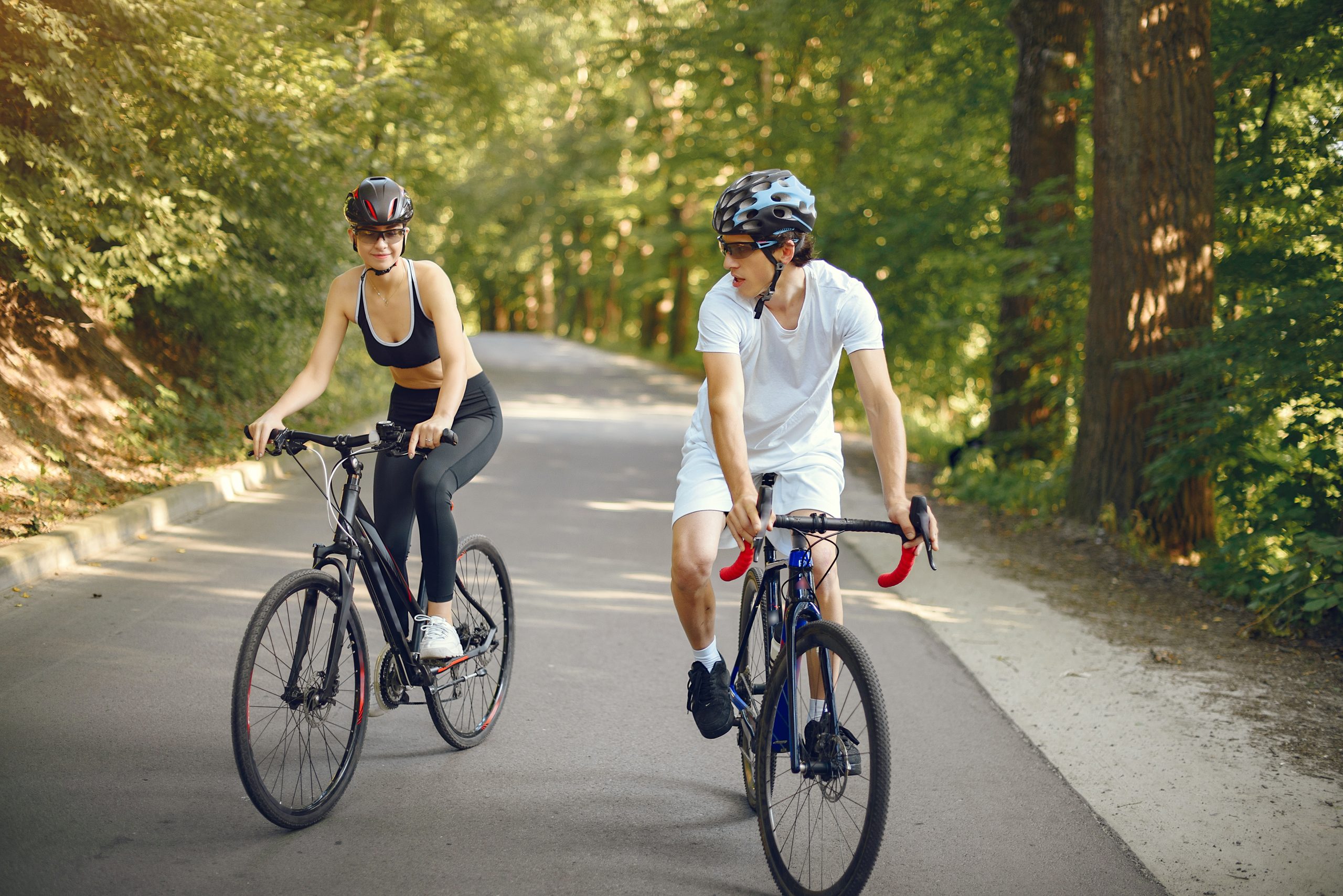 Sports_Couple_Riding_Bikes_Summer_Forest a couple riding bikes through the trees