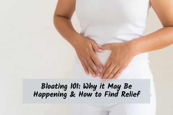 How_To_Reduce_Bloating Woman in white holding her abdomen trying to reduce bloating