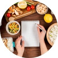 Nutrition_Goals_Seminar a pen on a notepad on a kitchen counter with food around it writing down nutrition goals for a seminar