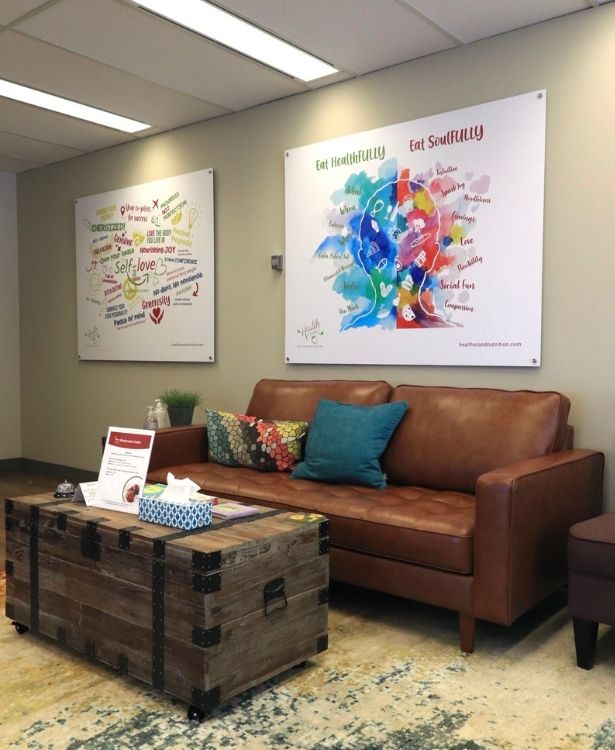Calgary_Dietitian_Office the entrance of Health Stand Nutrition Calgary Dietitian's Office with a brown couch a coffee table with books and brand images on the wall