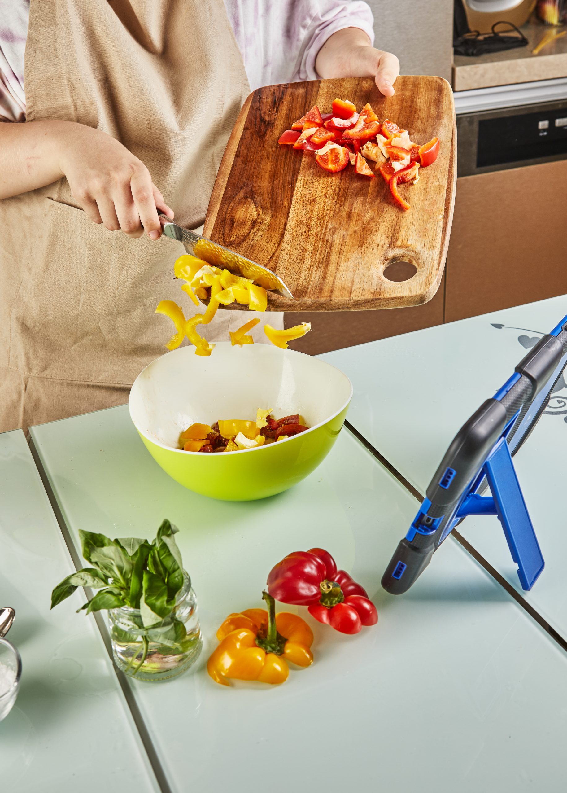 Teenager prepares salad from an online tutorial and watches digital recipe on touch tablet while preparing healthy meal in the kitchen at home Woman prepares veggies from an online tutorial and watches digital recipe on touch tablet while preparing healthy meal in the kitchen at home for weight management
