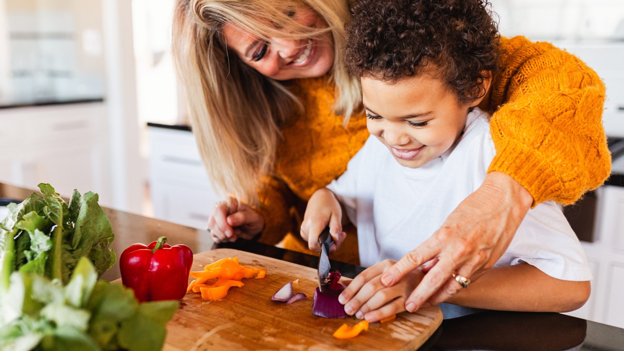 Parent and child cutting vegetables together