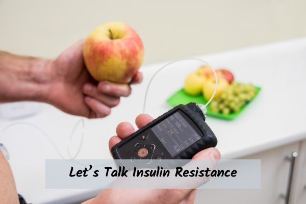 Someone holding a glucose meter and an apple