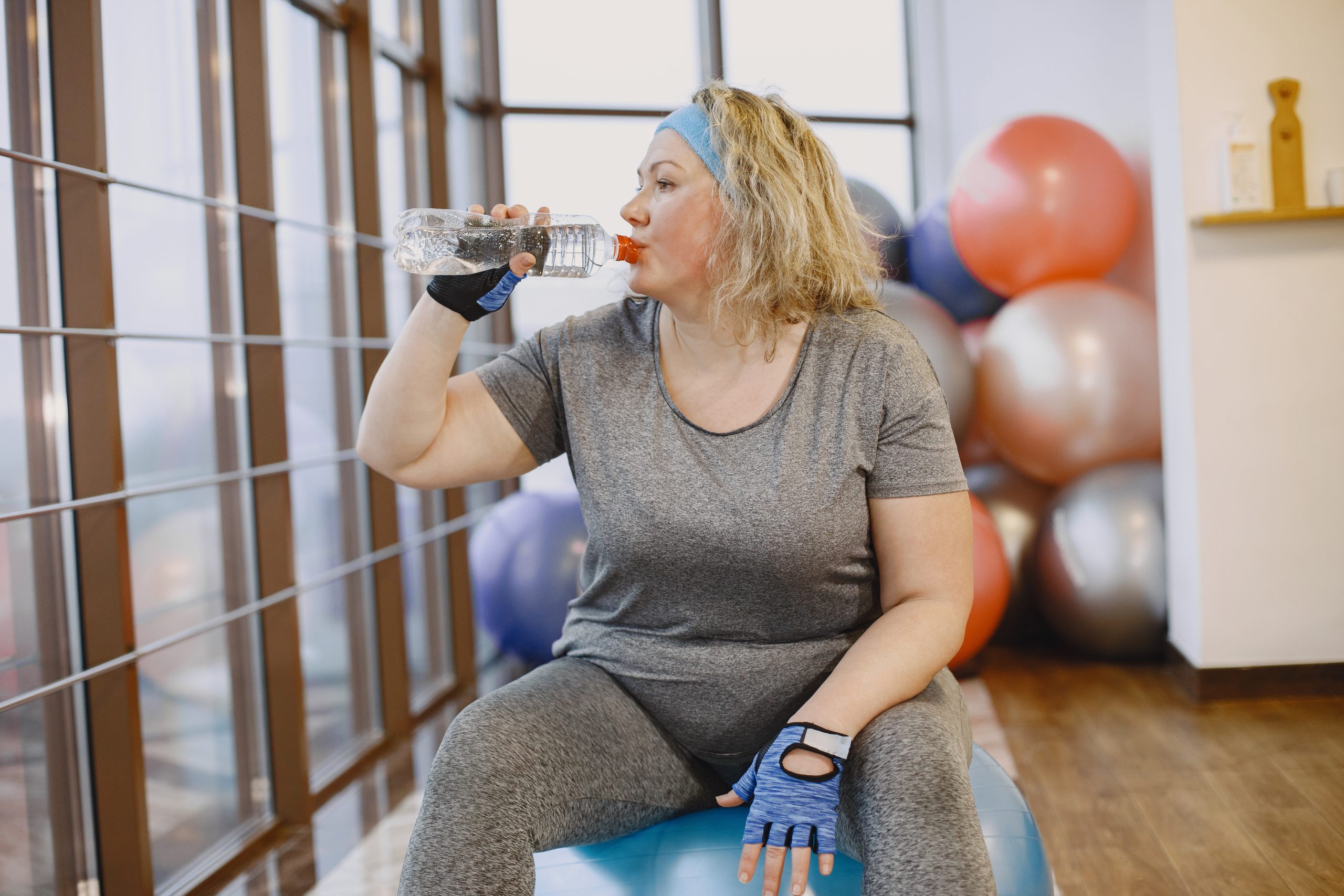 Menopausal woman have a rest at the gym drinking creatine water Menopausal women working out and drinking water with creatine in it.